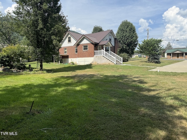 view of side of home with a yard, brick siding, and metal roof