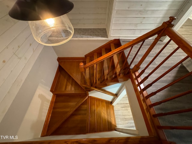 stairway featuring wooden walls