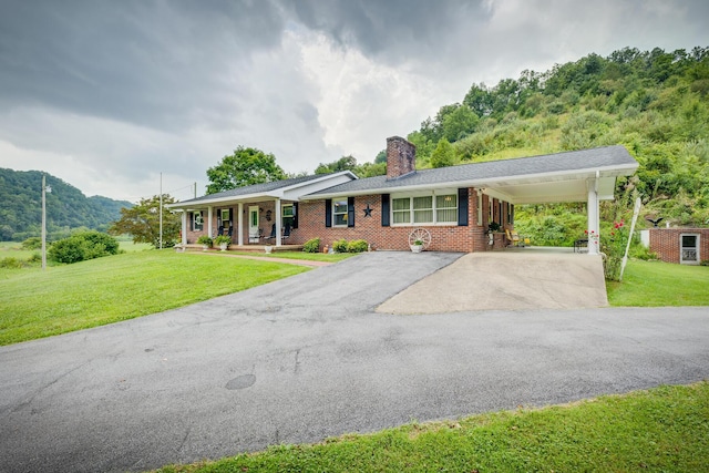 ranch-style house with a carport, a mountain view, a porch, and a front lawn