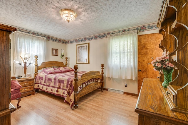 bedroom with a textured ceiling, light hardwood / wood-style flooring, and multiple windows