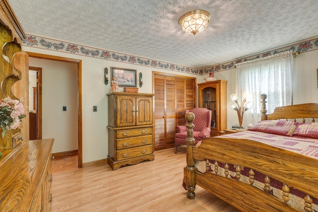 bedroom featuring light hardwood / wood-style floors, a textured ceiling, and a closet