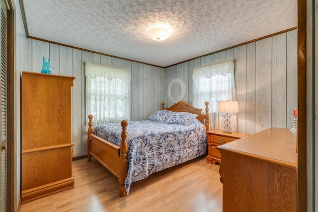 bedroom with a textured ceiling, light hardwood / wood-style flooring, and crown molding