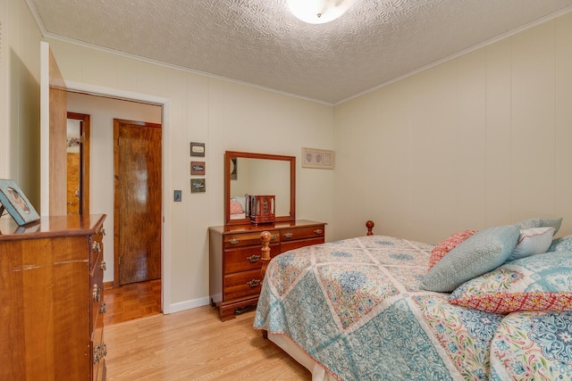 bedroom featuring a textured ceiling, light hardwood / wood-style flooring, and ornamental molding