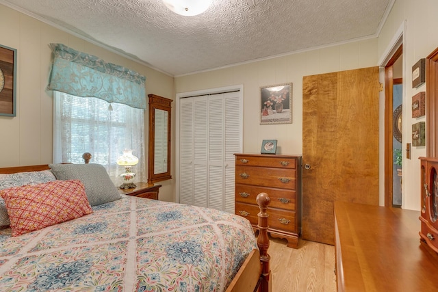 bedroom with wood walls, a textured ceiling, hardwood / wood-style flooring, a closet, and ornamental molding