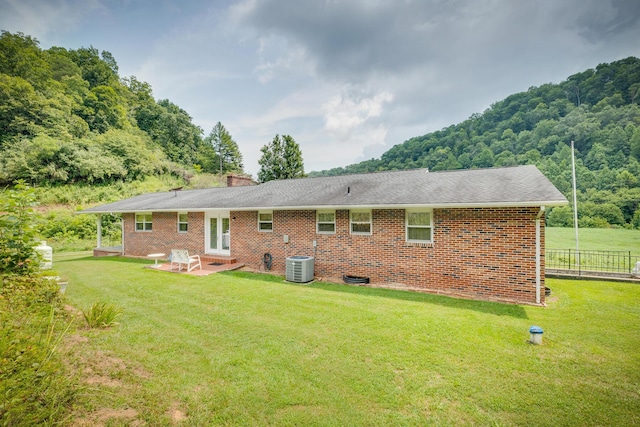 back of property with a lawn, a patio area, and central AC