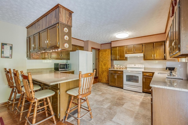 kitchen with kitchen peninsula, a textured ceiling, white appliances, a kitchen bar, and decorative backsplash