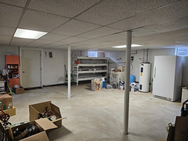 basement featuring a paneled ceiling, water heater, and white fridge