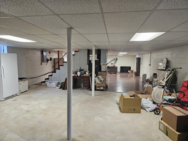 basement with a paneled ceiling and white refrigerator