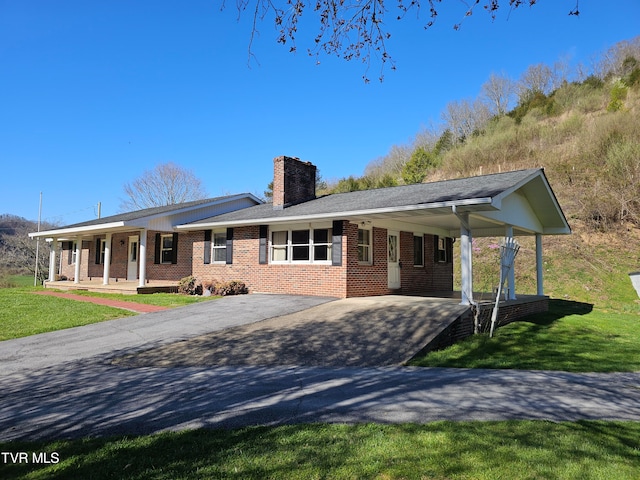 ranch-style home featuring covered porch, a carport, and a front yard