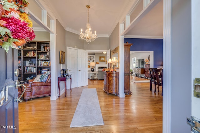 foyer entrance featuring crown molding, light hardwood / wood-style floors, and an inviting chandelier