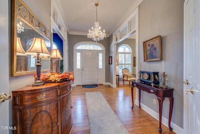 foyer entrance featuring an inviting chandelier, crown molding, and light wood-type flooring