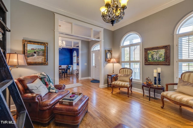 living room with a notable chandelier, ornamental molding, and light hardwood / wood-style floors