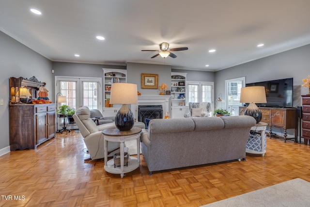 living room with ceiling fan, light parquet floors, built in shelves, and a wealth of natural light