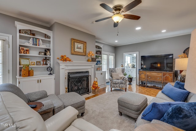 living room with light parquet flooring, a high end fireplace, ceiling fan, and crown molding