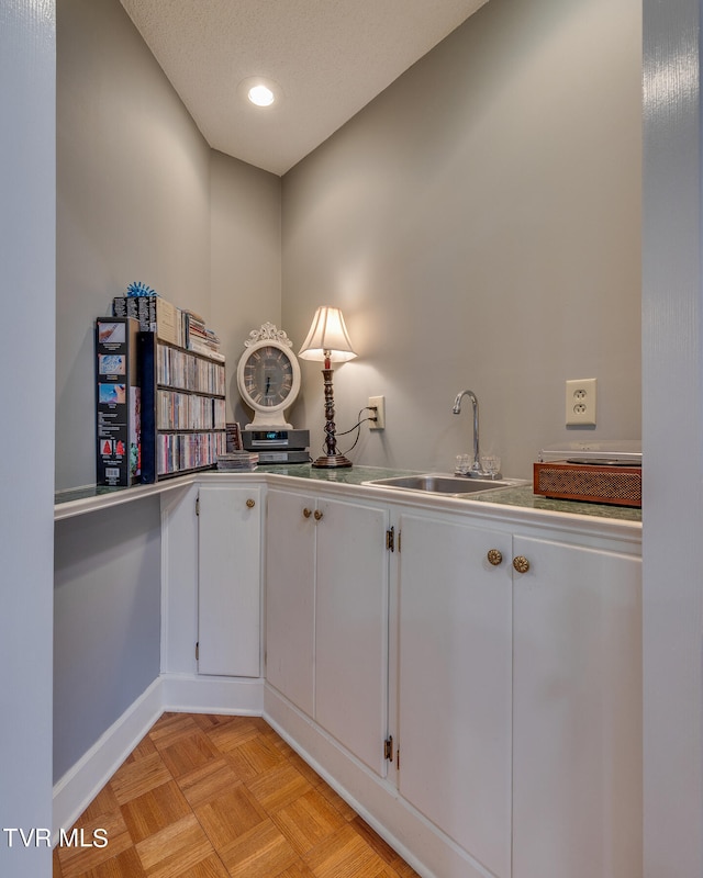 interior space with light parquet flooring, sink, white cabinetry, and a textured ceiling