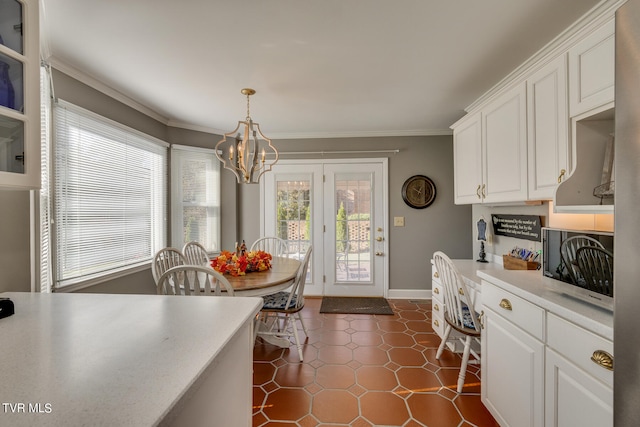 kitchen with dark tile flooring, white cabinetry, a notable chandelier, and pendant lighting