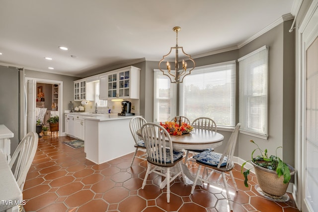 dining area with plenty of natural light, dark tile floors, ornamental molding, and a notable chandelier