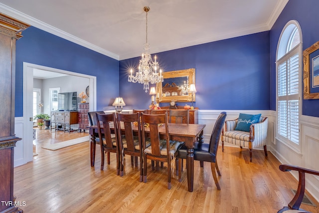 dining room featuring a notable chandelier, ornamental molding, and light hardwood / wood-style floors