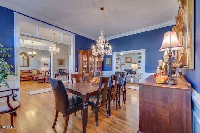 dining space featuring light hardwood / wood-style flooring, ornamental molding, and a chandelier