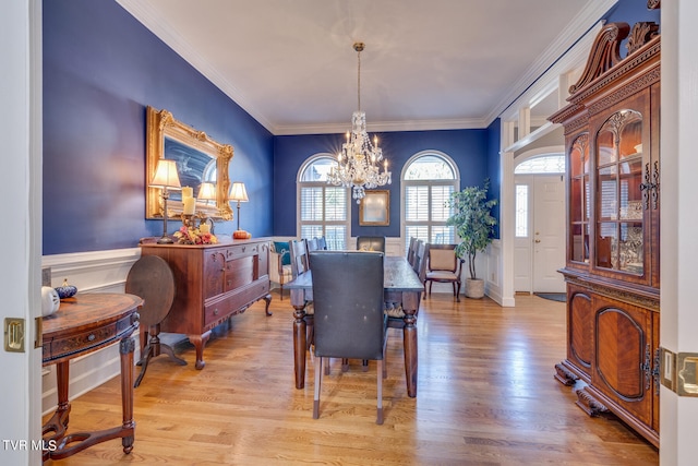 dining area with light hardwood / wood-style flooring, ornamental molding, and a chandelier