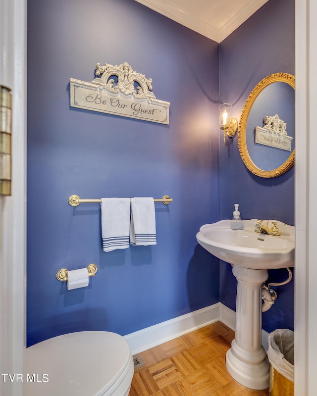 bathroom with parquet flooring, toilet, and ornamental molding