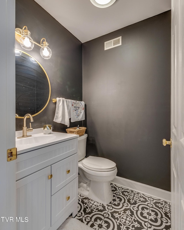 bathroom with toilet, vanity, and tile flooring