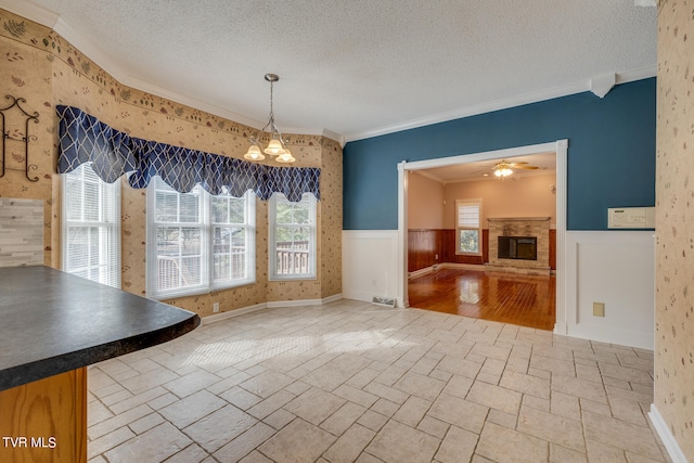 unfurnished dining area with a wealth of natural light, ornamental molding, a textured ceiling, and light tile patterned floors