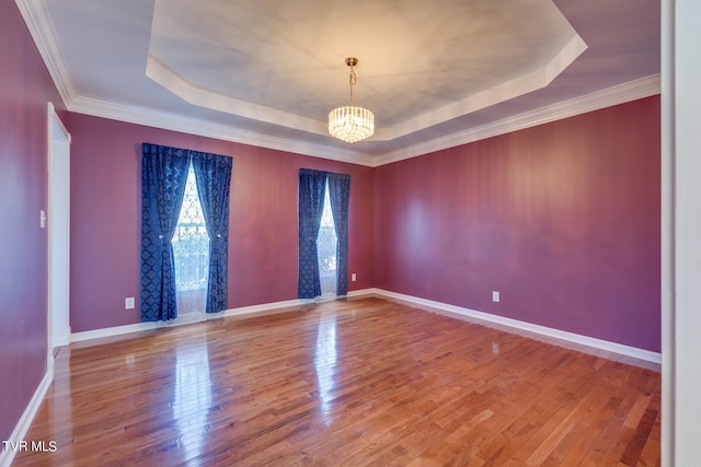 unfurnished room with hardwood / wood-style floors, a notable chandelier, ornamental molding, and a tray ceiling