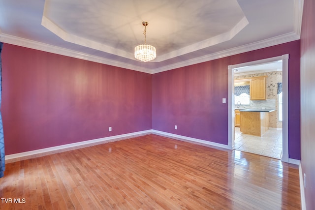 empty room featuring a notable chandelier, a raised ceiling, light tile patterned floors, and ornamental molding