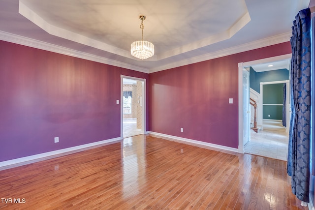 unfurnished room with tile patterned flooring, a tray ceiling, a notable chandelier, and crown molding