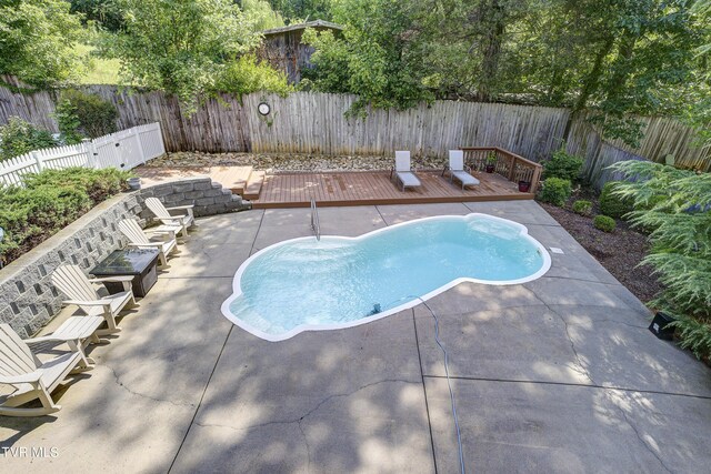 view of swimming pool with a wooden deck and a patio