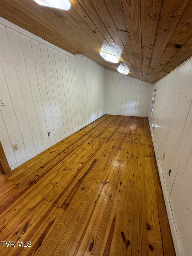 interior space with light hardwood / wood-style floors, wooden ceiling, and wood walls