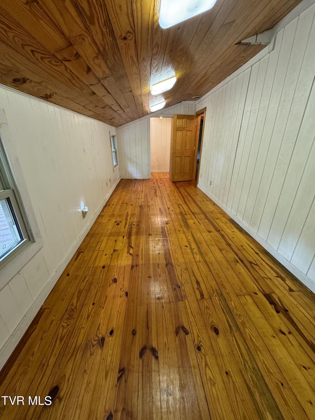 bonus room featuring wood walls, lofted ceiling, light hardwood / wood-style floors, and wooden ceiling