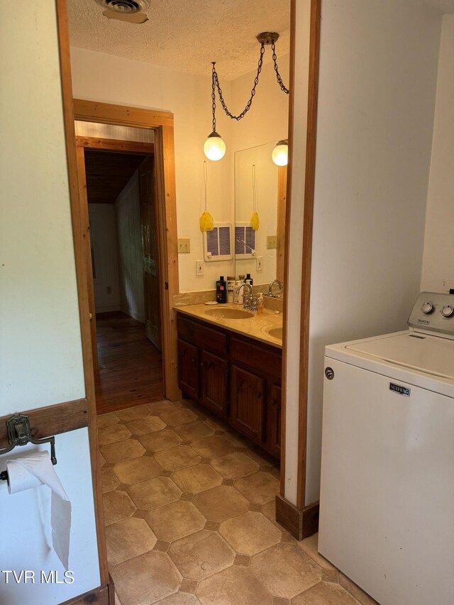 washroom with a textured ceiling, light wood-type flooring, sink, and washer / clothes dryer