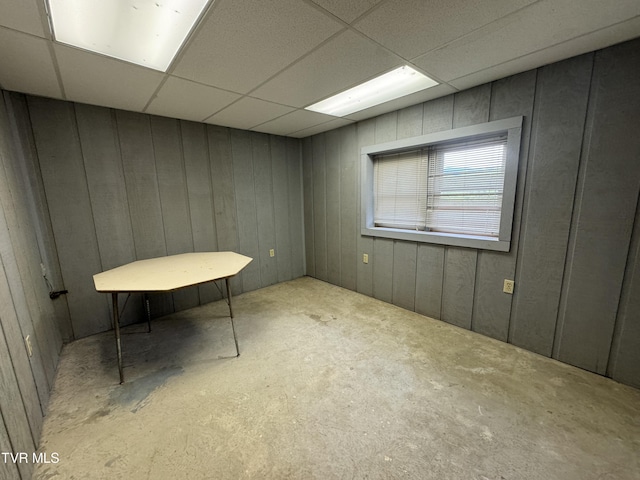 interior space with a paneled ceiling and wooden walls