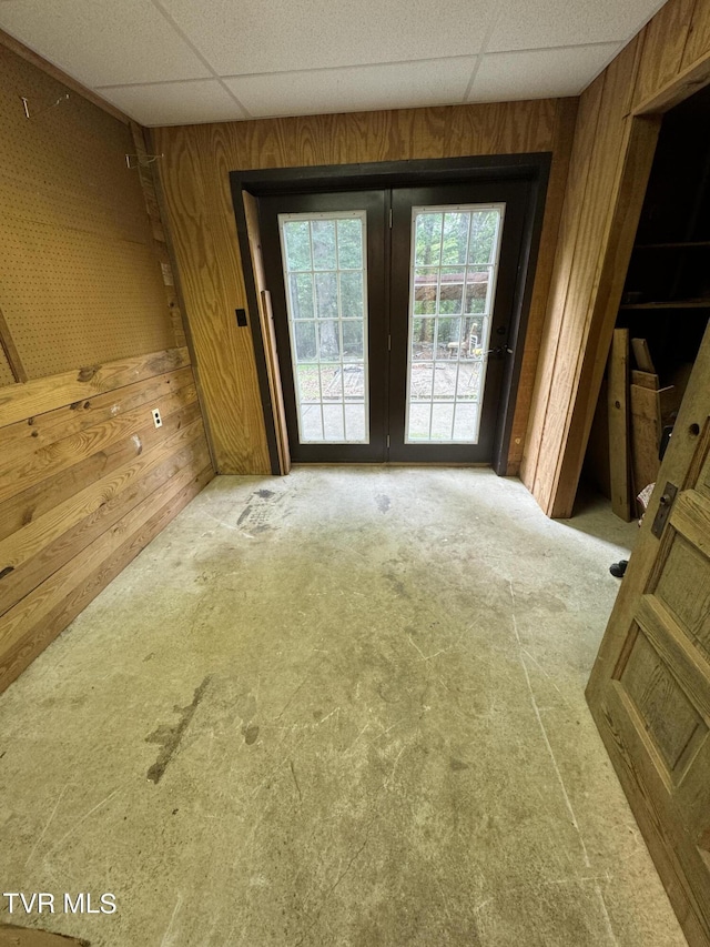 interior space with a paneled ceiling and wooden walls