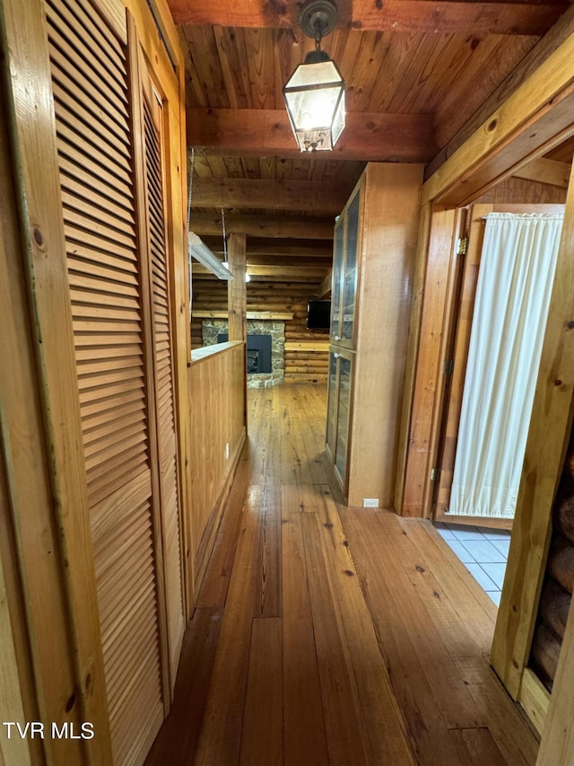 corridor featuring beam ceiling, wood-type flooring, and wooden ceiling