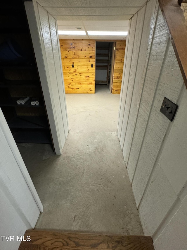 hall with concrete flooring and wood walls