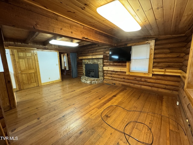 unfurnished living room with rustic walls, hardwood / wood-style floors, wooden ceiling, and a wood stove