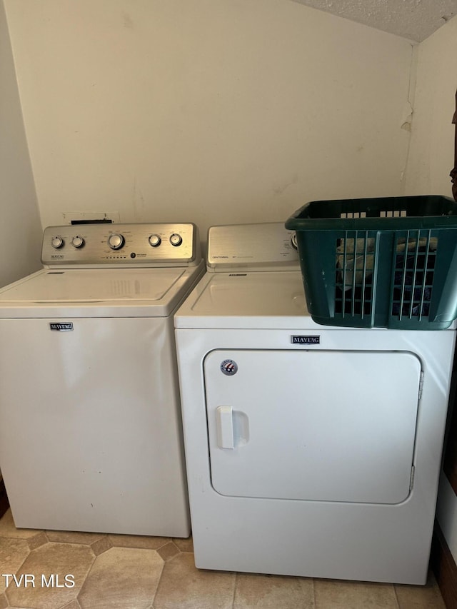 laundry room featuring washer and dryer, light tile patterned floors, and a textured ceiling