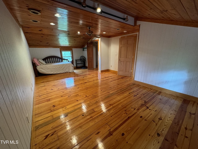 unfurnished bedroom with wooden walls, light hardwood / wood-style flooring, wooden ceiling, and vaulted ceiling