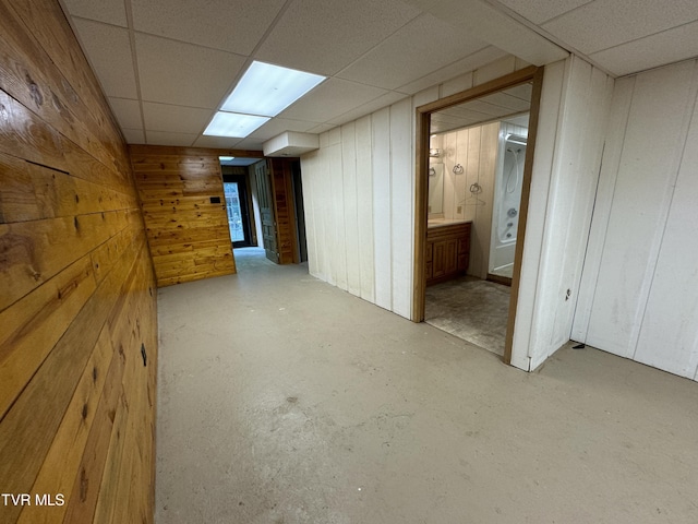 interior space with a drop ceiling and wooden walls