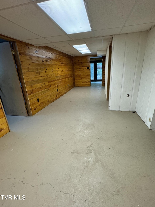 basement featuring a drop ceiling and wooden walls