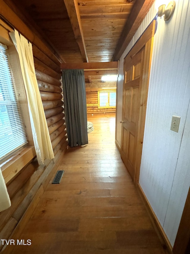 corridor featuring hardwood / wood-style floors, beam ceiling, wooden ceiling, and a wealth of natural light