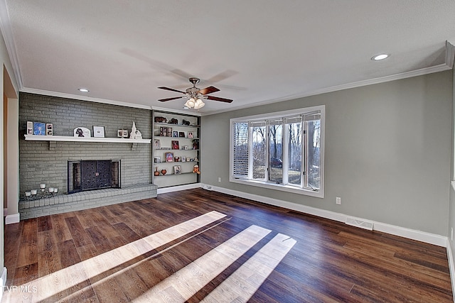 unfurnished living room with ceiling fan, a fireplace, brick wall, crown molding, and dark hardwood / wood-style floors