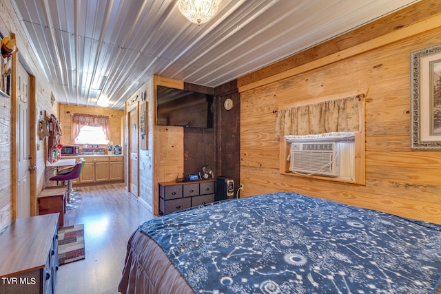 bedroom featuring an inviting chandelier, wood walls, and light hardwood / wood-style floors