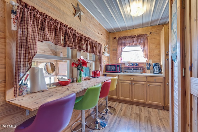 kitchen with light hardwood / wood-style flooring, sink, light brown cabinets, and wood walls