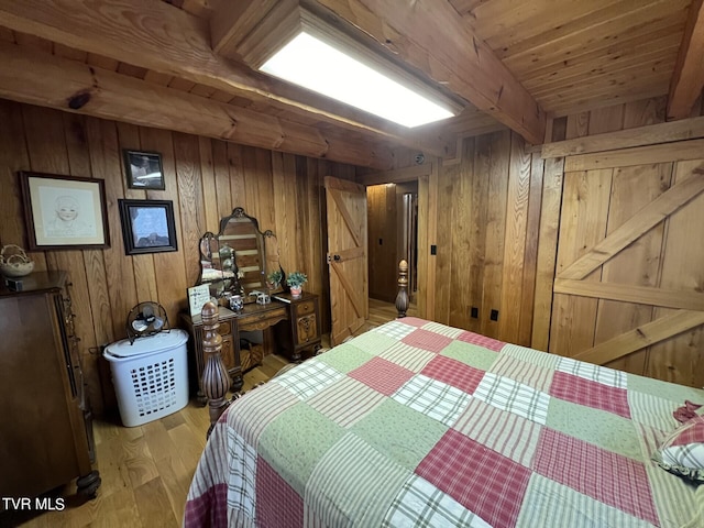 bedroom with wood walls, beam ceiling, wooden ceiling, and light hardwood / wood-style floors