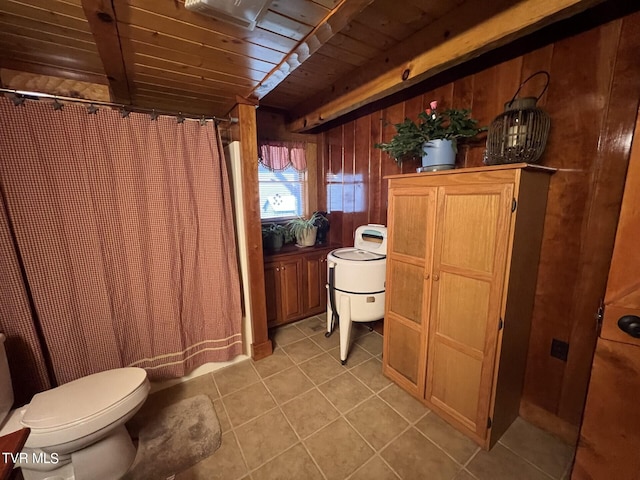 bathroom with wood walls, wooden ceiling, tile patterned flooring, toilet, and beam ceiling