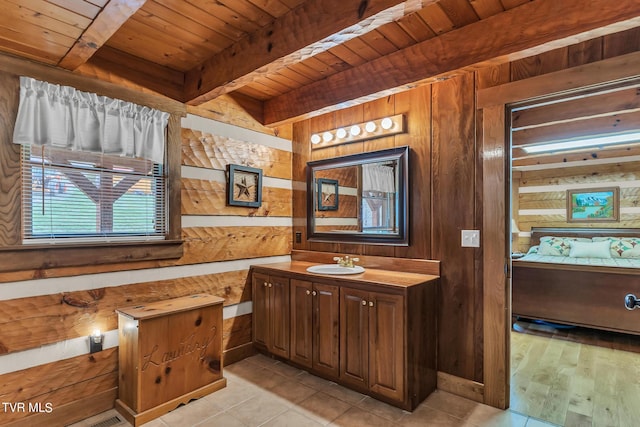 bathroom featuring vanity, wooden ceiling, wooden walls, tile patterned flooring, and beam ceiling